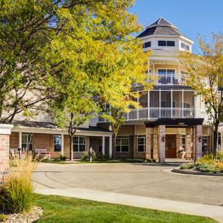 A multi-story building with a welcoming entrance surrounded by trees and a driveway.