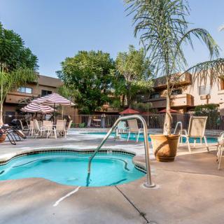 An inviting outdoor swimming area featuring a pool and hot tub surrounded by patio furniture and palm trees on a sunny day.