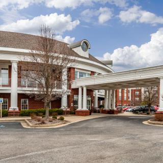 A large hotel building with a circular driveway and prominent entrance against a partly cloudy sky.