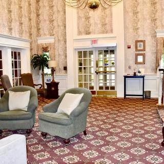 A traditional lobby interior with upholstered chairs and patterned carpet.