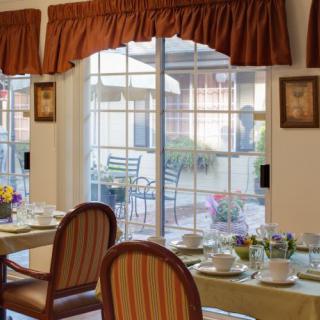A well-set dining area with elegant chairs and a view of the outdoor patio through large windows.