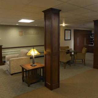 A cozy lobby with comfortable seating, a wooden column, and warm lighting.