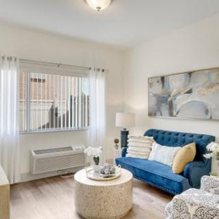 A cozy and modern living room featuring a blue sofa, elegant coffee table, and ample natural light.