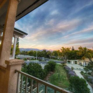 A tranquil sunset view from a balcony overlooking lush greenery and distant hills.