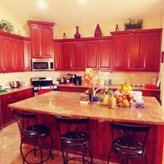 A spacious kitchen with wooden cabinets and a central island adorned with fruit and decor.