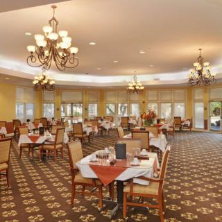 An elegant restaurant dining room with neatly arranged tables and chandeliers.