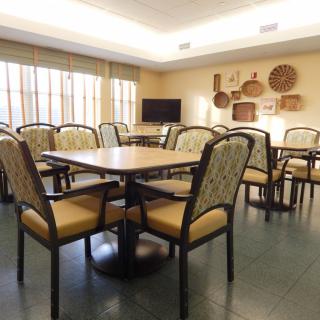 A well-lit dining room with multiple tables and chairs, decorated with wall baskets.
