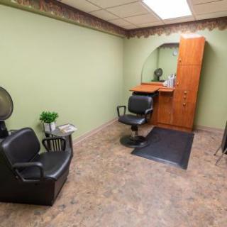 A cozy and well-lit salon area with black chairs and a wooden cabinet.