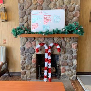 A cozy stone fireplace adorned with festive Christmas decorations, including a whiteboard and candy cane accents.