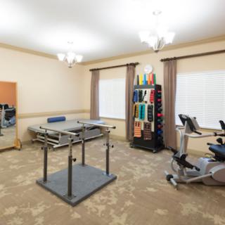 A rehabilitation room equipped with various therapy tools and exercise equipment, including a therapy table and exercise bikes.