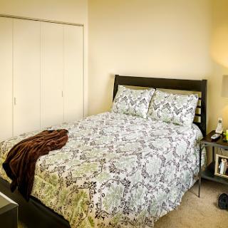 A cozy bedroom featuring a neatly made bed with patterned bedding and a bedside lamp.