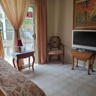 A cozy living room with a television, elegant furniture, and large windows covered by sheer curtains.