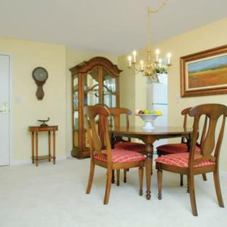 A traditional dining room with a wooden table and chairs, a chandelier, and a cabinet against the wall.