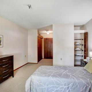 A cozy and well-lit bedroom featuring a neatly made bed, dresser, and access to a closet.