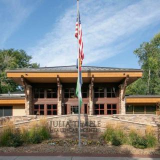 Front view of a school building with an American flag and trees surrounding it.