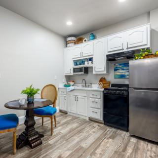 A modern apartment kitchen with white cabinets, stainless steel appliances, and a small dining area.