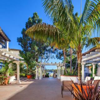 A sunny outdoor garden patio with palm trees and seating areas.