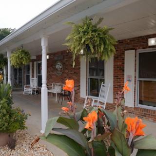 A charming porch adorned with vibrant flowers and lush hanging plants, showcasing a welcoming outdoor space.