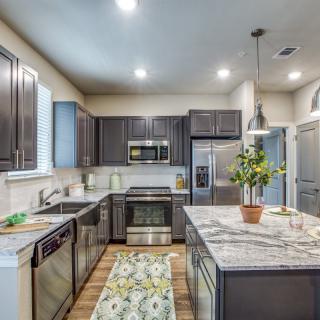 A modern kitchen with dark cabinetry, a central island, and stainless steel appliances.