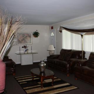 A cozy living room featuring dark sofas, a glass coffee table, and decorative elements such as a large vase and wall art.