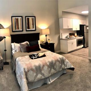 A cozy studio apartment with a modern bedroom and a kitchenette.
