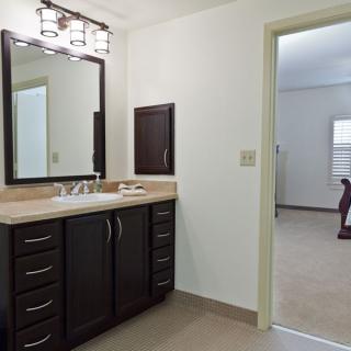 A modern bathroom with a dark wood vanity and stylish lighting.