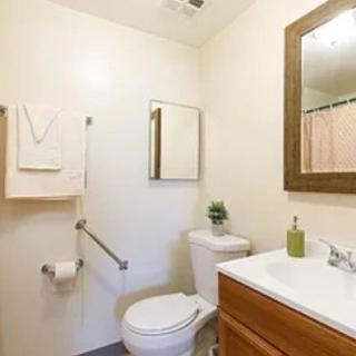 A simple and clean bathroom with a toilet, sink, and mirror.