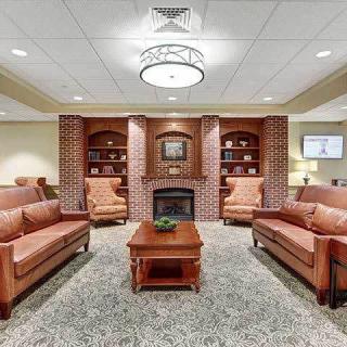 A cozy living room with two sofas, armchairs, a central coffee table, and a fireplace surrounded by bookshelves.