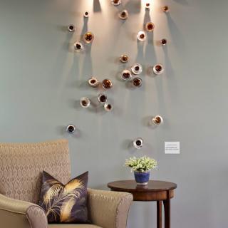 A cozy living room corner featuring modern wall art, a comfortable chair, and a side table with decorative items.