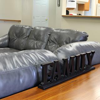 A cozy living room with a gray couch and a 'FAMILY' sign on display.
