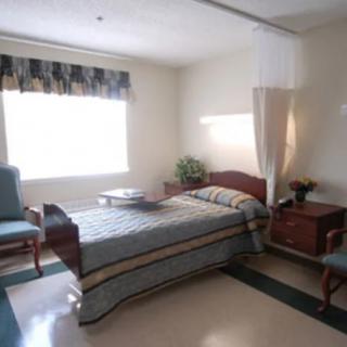 A clean and well-lit hospital room with a single bed and minimal furnishings.
