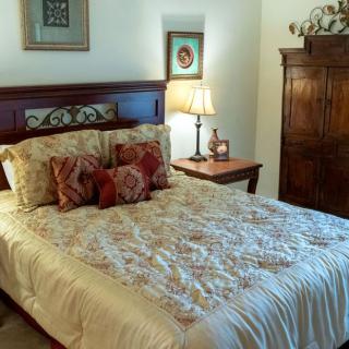 A cozy bedroom with a neatly made bed, decorative pillows, and warm lighting.