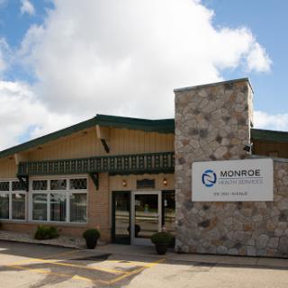 Exterior view of a modern business building with a stone facade and signage.
