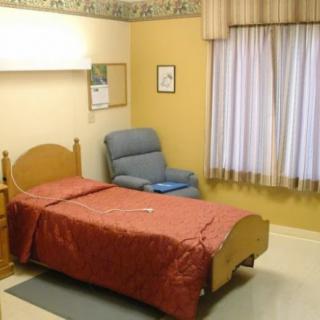 A tidy hospital room with a single bed and chair.