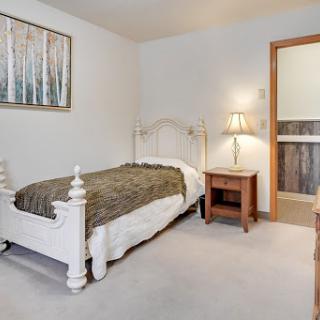 A cozy bedroom featuring a single bed with a decorative blanket, complemented by a bedside lamp and artwork on the wall.