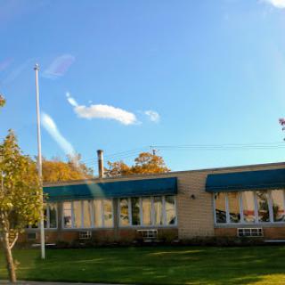 A sunny day showcasing a building with green awnings and a flagpole in front.