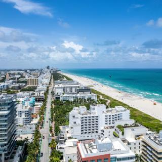 A vibrant view of the Miami coastline, showcasing the beautiful beach and cityscape under a bright blue sky.