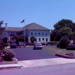 A building with an American flag and a parking lot in the foreground.