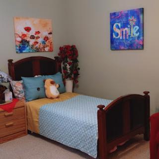 A cozy and colorful bedroom featuring a wooden bed, decorative pillows, and cheerful wall art.
