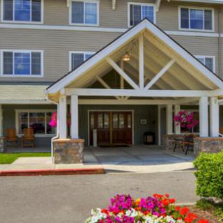 A welcoming entrance to a residential building, featuring neatly arranged landscaping and colorful flowers.