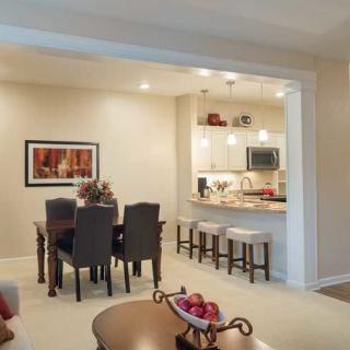 A modern dining area connected to a compact kitchen with bar stools and a cozy ambiance.