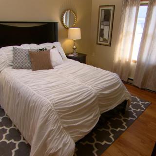 A cozy bedroom with a neatly made bed, stylish decor, and natural lighting.