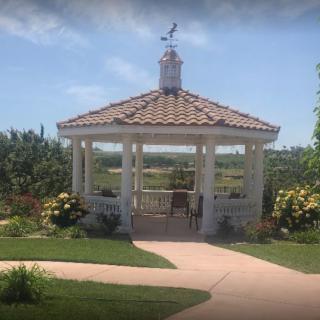 A charming gazebo set in a lush garden with clear blue skies.