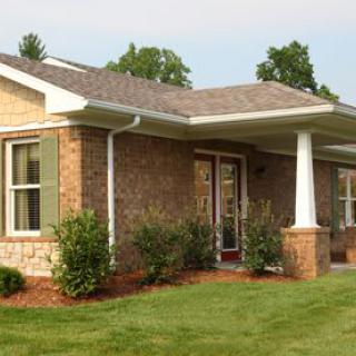 A suburban brick house with a well-maintained yard and landscaping.