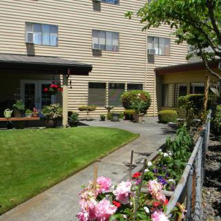 A serene garden with colorful flowers and a well-maintained pathway beside a residential building.