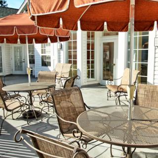 A sunny patio with outdoor seating, featuring tables and chairs under umbrellas.
