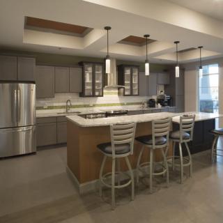 A modern kitchen with a central island, featuring pendant lighting and stainless steel appliances.