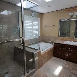A modern bathroom featuring a glass-enclosed shower, a separate bathtub, and a large mirror above a wooden cabinet.