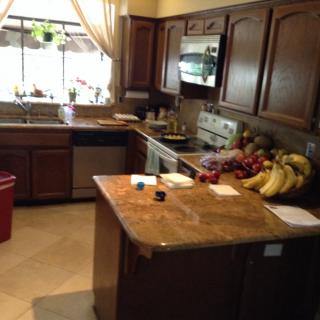 A cozy kitchen with wooden cabinets, a central island, and fresh fruits on the counter.