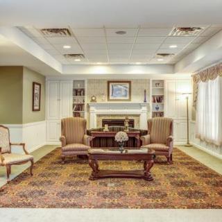 A traditional living room featuring comfortable armchairs and a classic coffee table set around a fireplace.